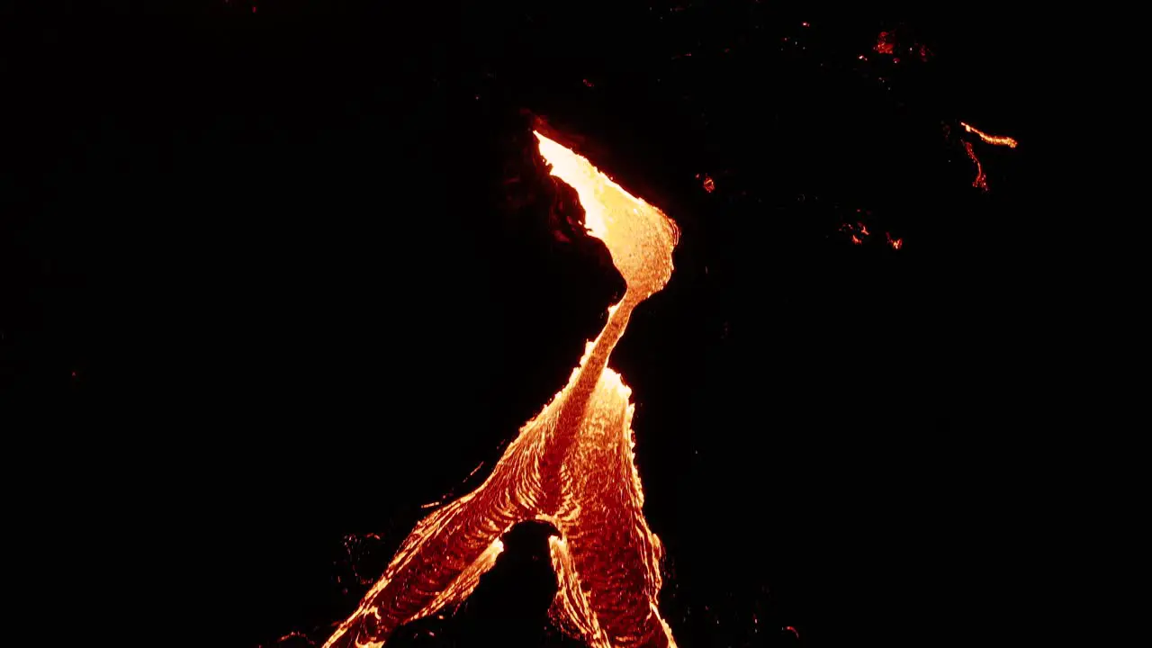 Lava river splits into two streams at night surrounded by basalt rock aerial