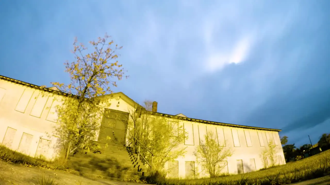 NIGHT LAPSE Clouds fly by fast over a old abandoned hospital at night