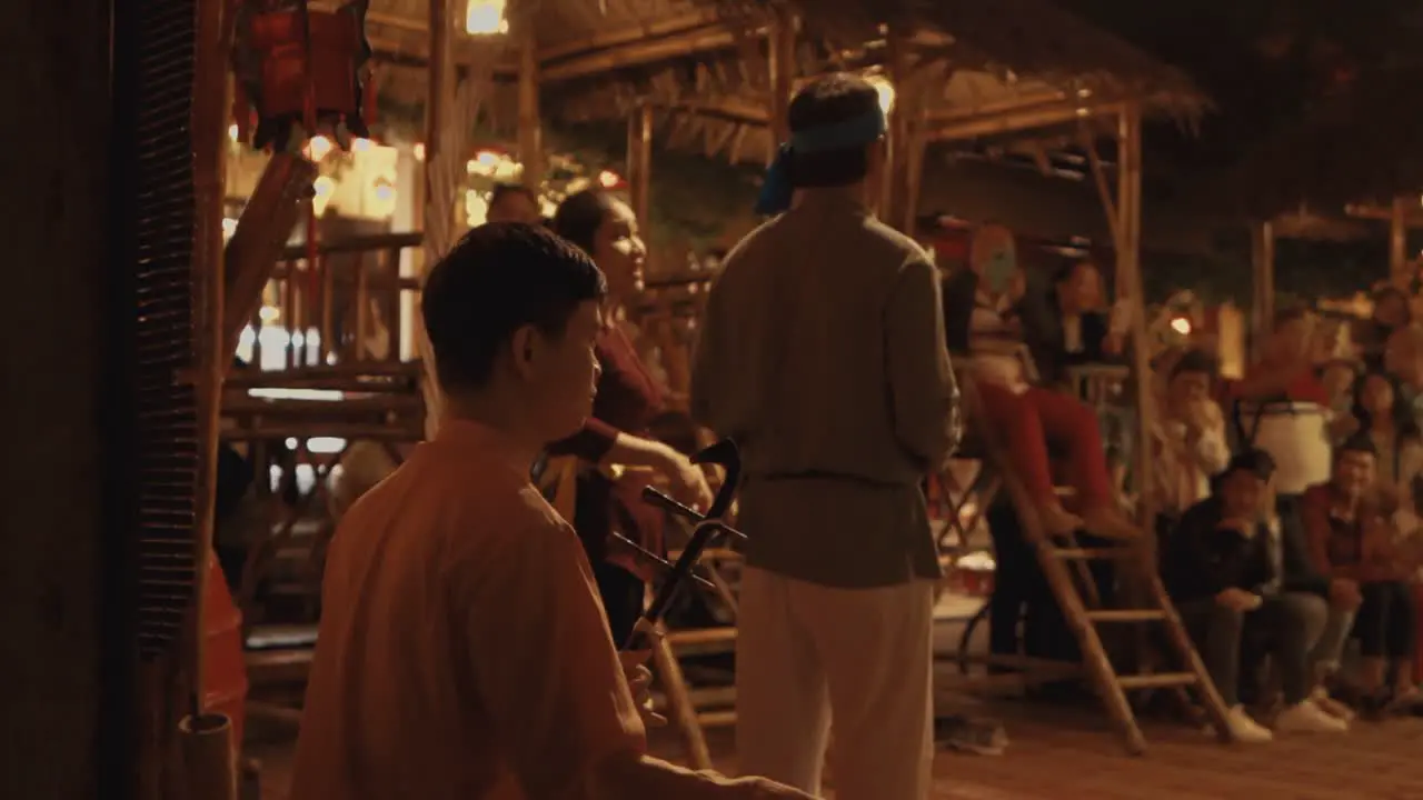 Crowd Listening to an Adult Male Playing Traditional Vietnamese Music