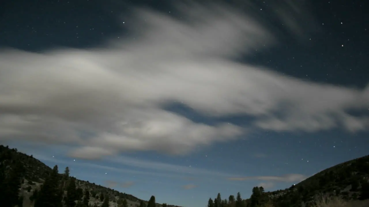 Fluffy white clouds race through a blue sky as it fades into darkness then returns with intense light