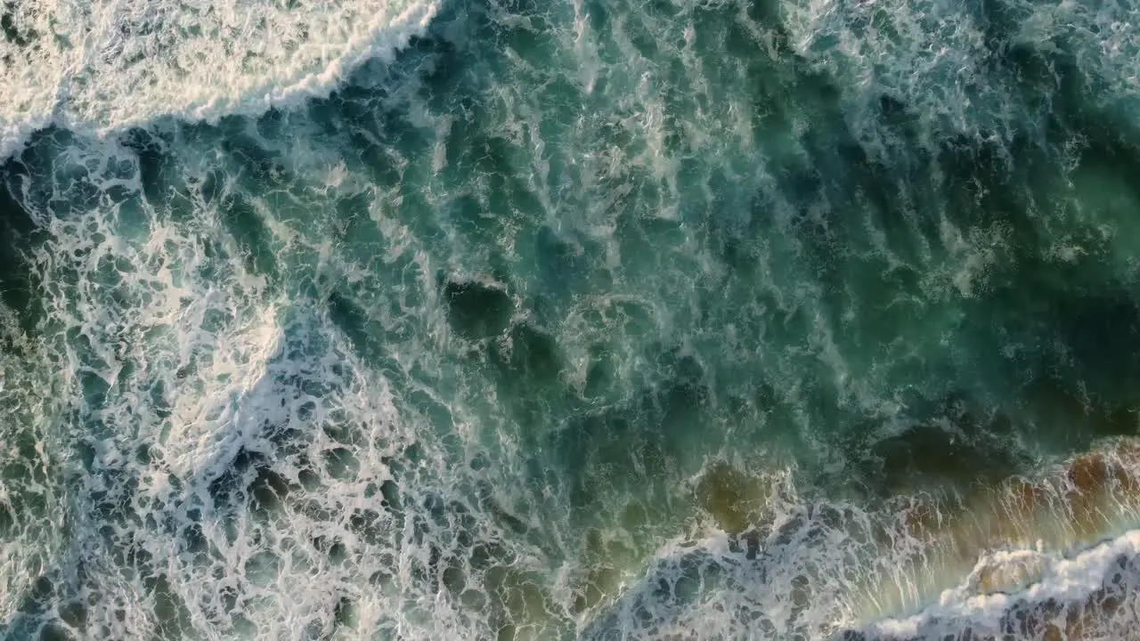 Bird's-eye view aerial drone view pan shot over ocean waves and sand at Shelly Beach Central Coast NSW Australia 3840x2160 4K