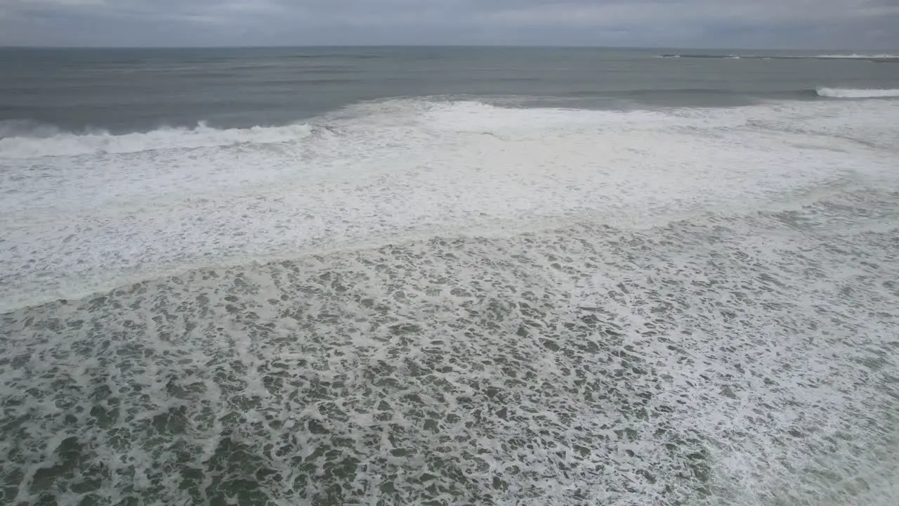 Aerial view of the sea with strong waves reaching sand beach