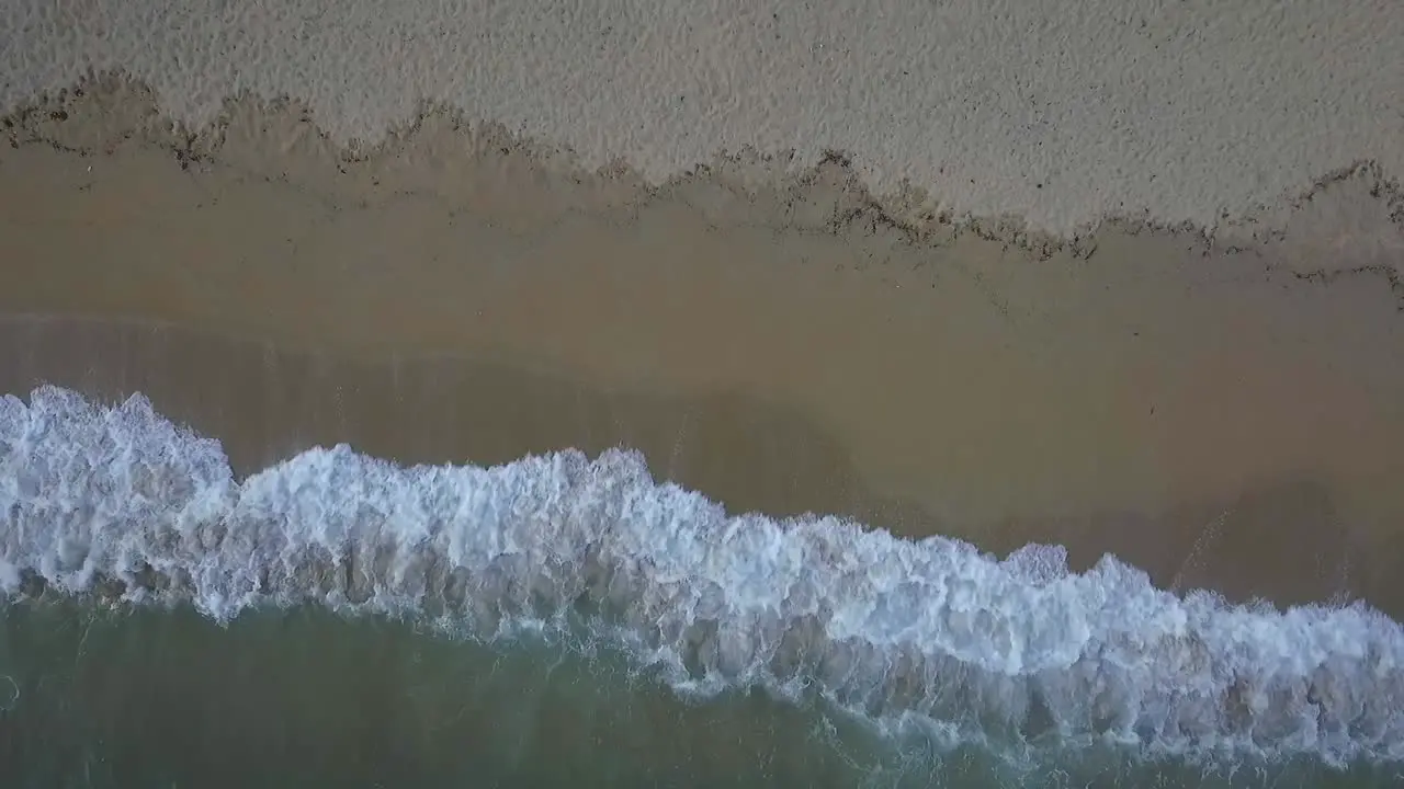 Amazing top aerial view of exotic vacation beach at dusk waves splash zoom out