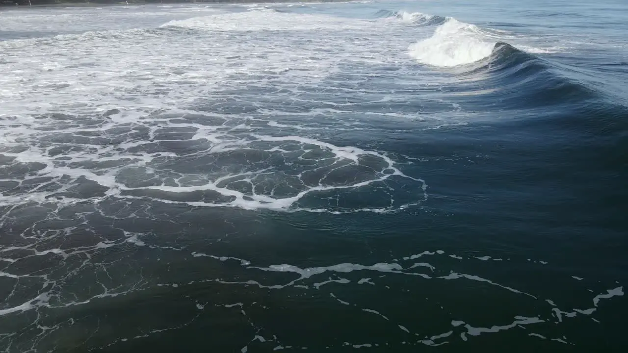 AERIAL Deep blue ocean swell crashes in front of camera