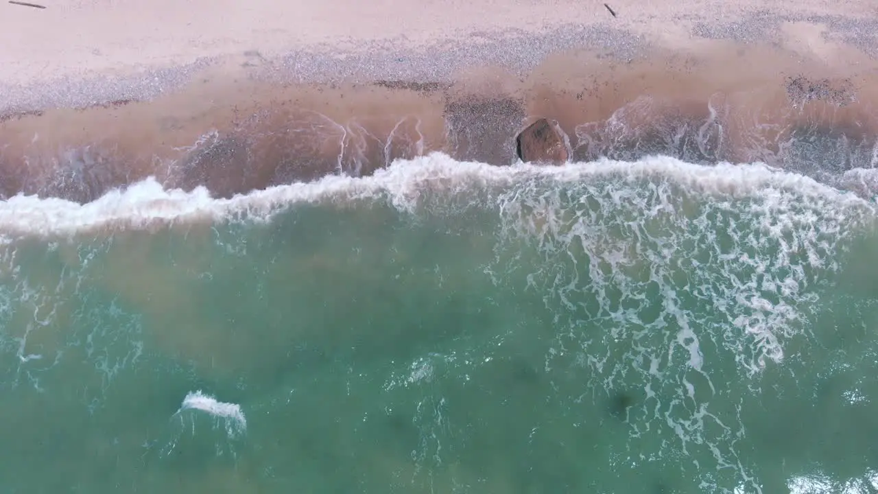 Static aerial of turquoise waves crashing and foaming on a tropical beach