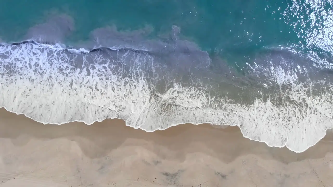 Aerial View Of Waves Crashing On sandy Beach during beautiful summer day