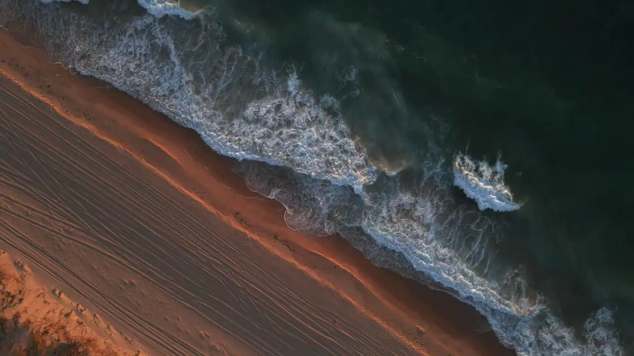 A dynamic high angle shot of the shoreline with strong waves of water during the golden hour