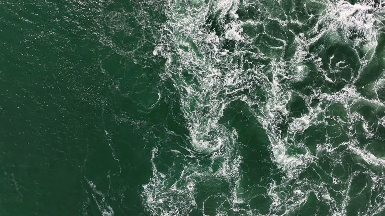 Aerial overhead shot of ocean waves splashing and crashing during sunny day