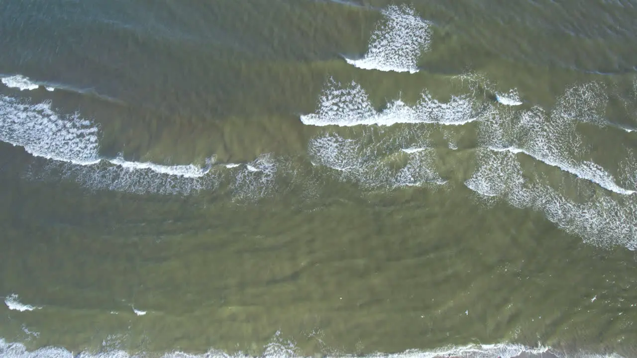 Aerial top down shot of breaking waves in Baltic Sea during sunny day