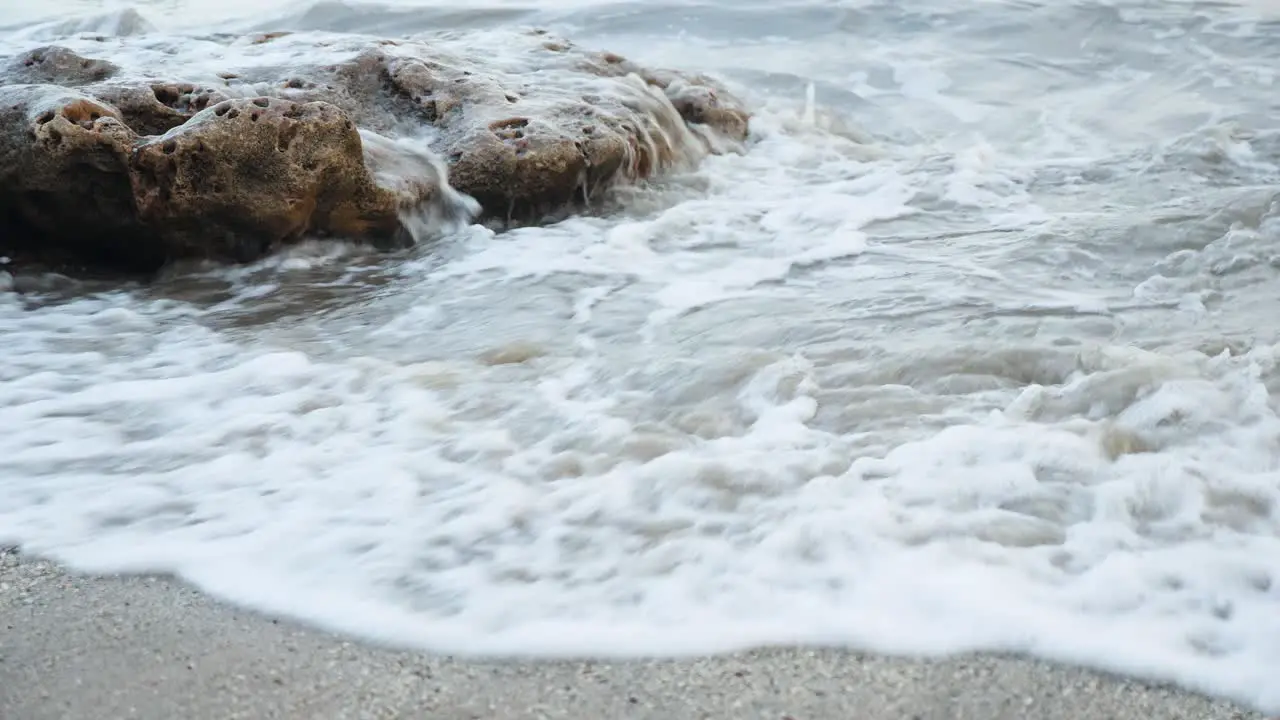 Waves crashing into a rock on the beach late in the evening on a sandy beach of India