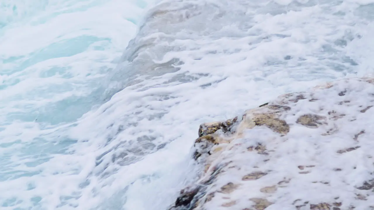 Sea waves crushing on rocky shore water pour over rocks close up