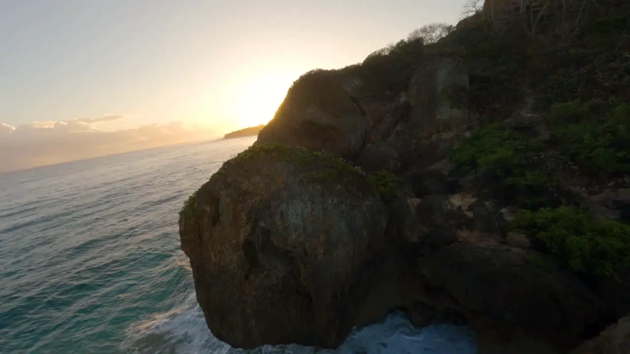 FPV drone footage of waves crashing on the rocks at sunrise