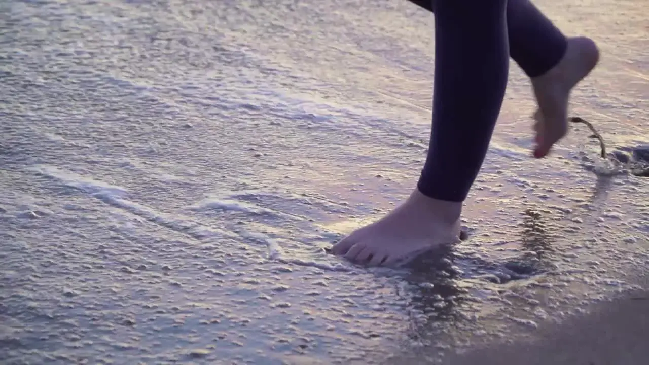 Females feet walking in the water on the beach for sunset