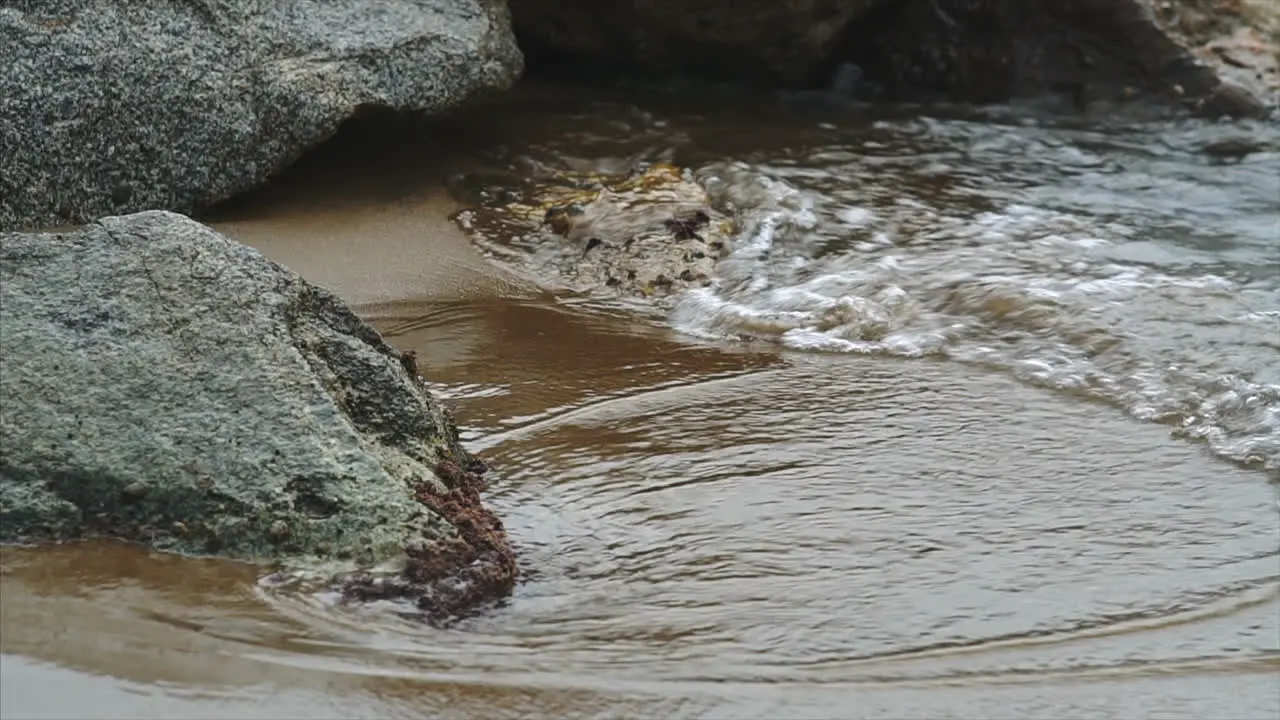 Slow Motion of Waves crashing on rocks with a sandy beach