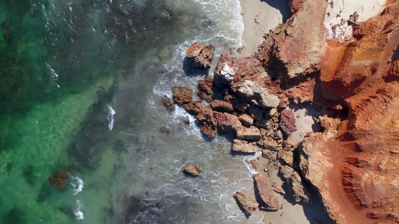 waves crashing agains red rock on the beach