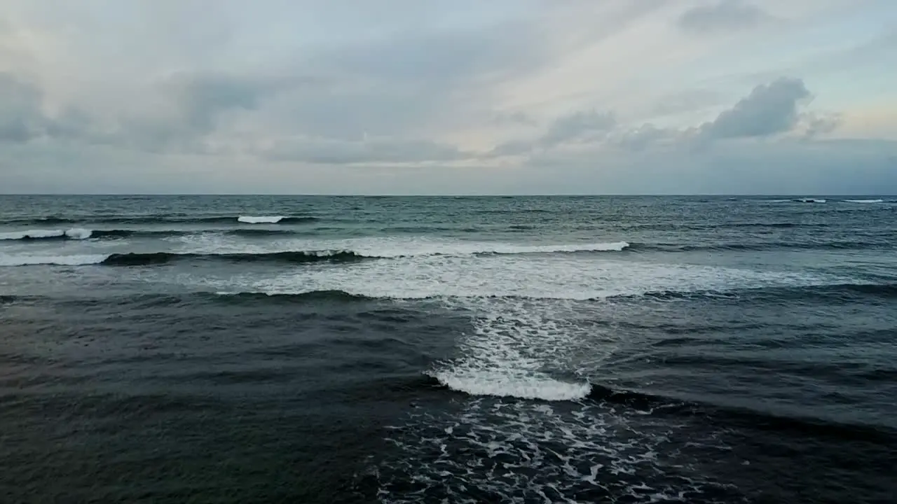 Aerial reveal of sea from snowy black rocks of Sandgerdi Iceland in January