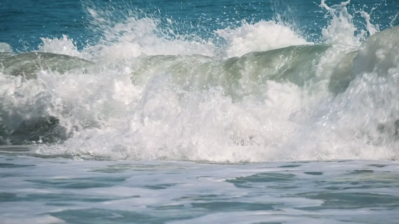 Slow motion shot of breaking giant ocean waves during sunlight and blue sky