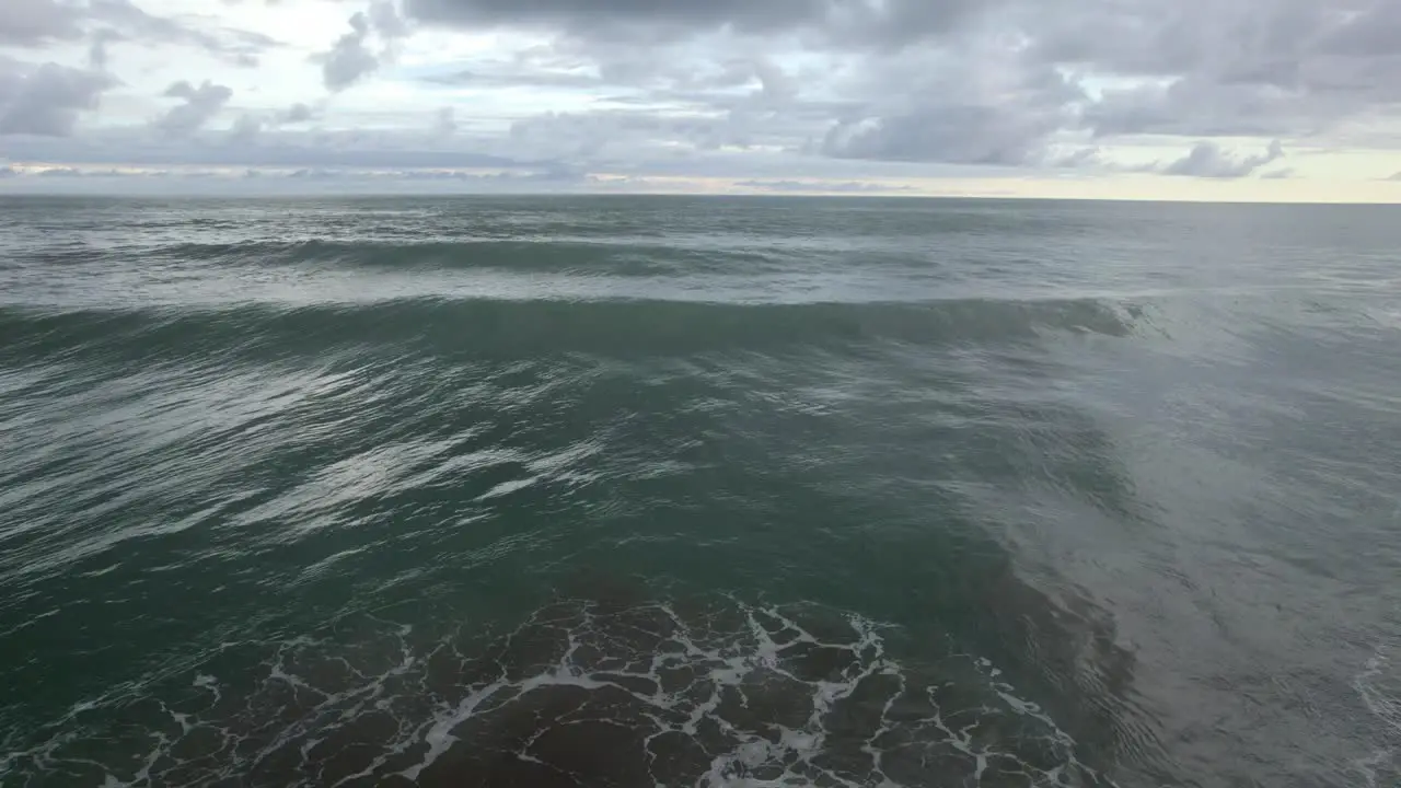 Aerial dolly in of foamy turquoise sea waves near the shore on an overcast day in Dominicalito Beach Costa Rica