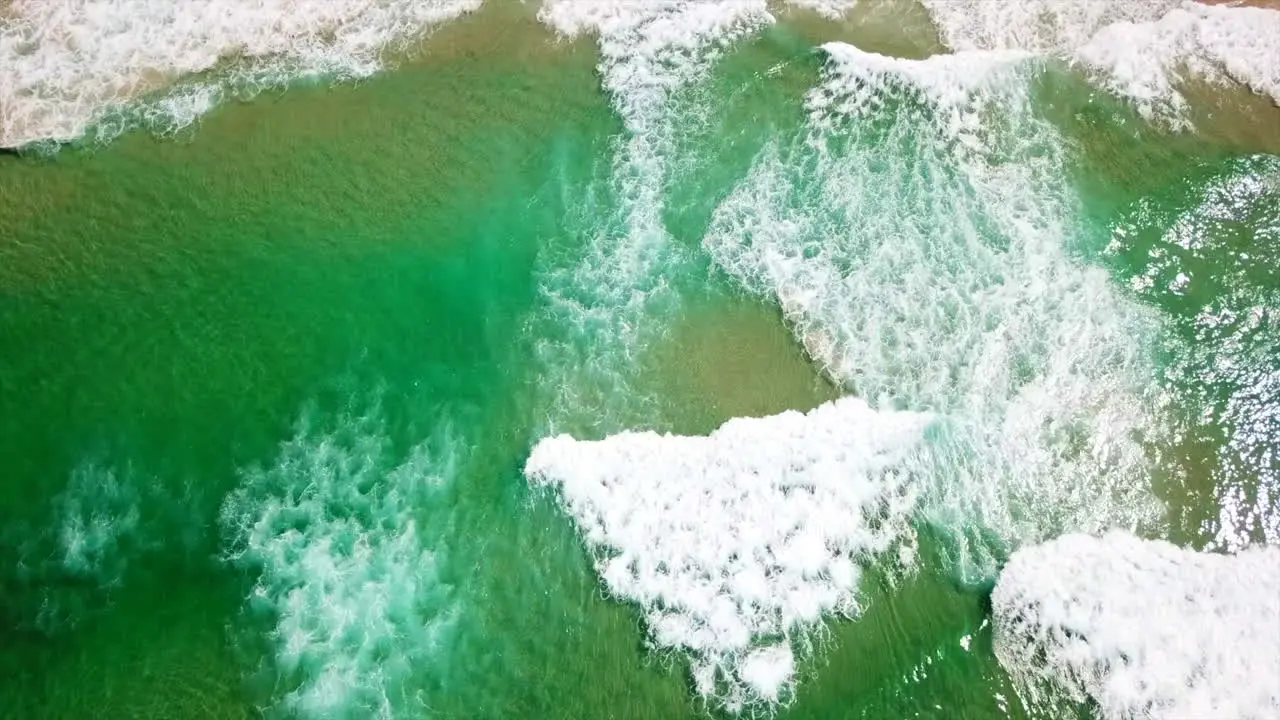 Aerial Drone shot over the ocean tilting up to reveal a sandy beach coastline near Byron Bay Australia