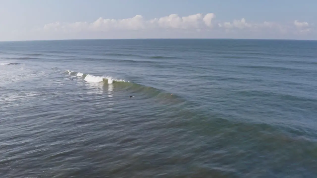 Aerial surfer paddling and catching large wave in sea high view