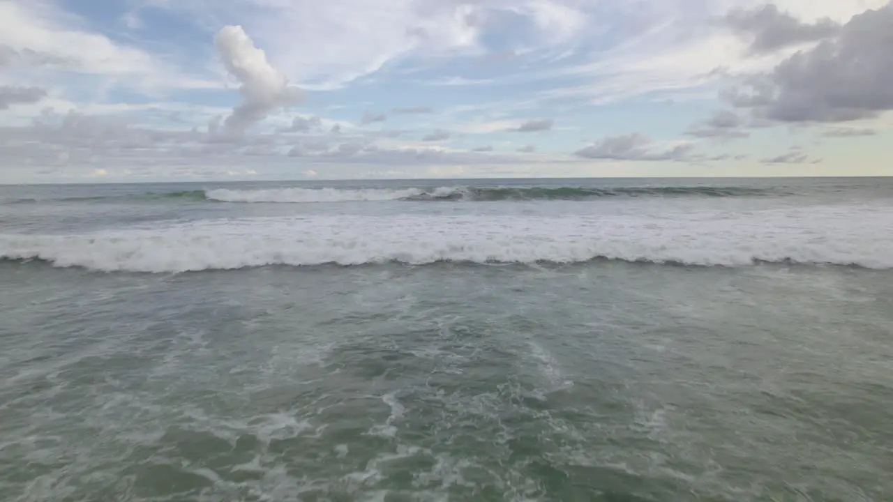 Aerial dolly in of foamy turquoise sea waves hitting the shoreline on a cloudy day in Dominicalito Beach Costa Rica