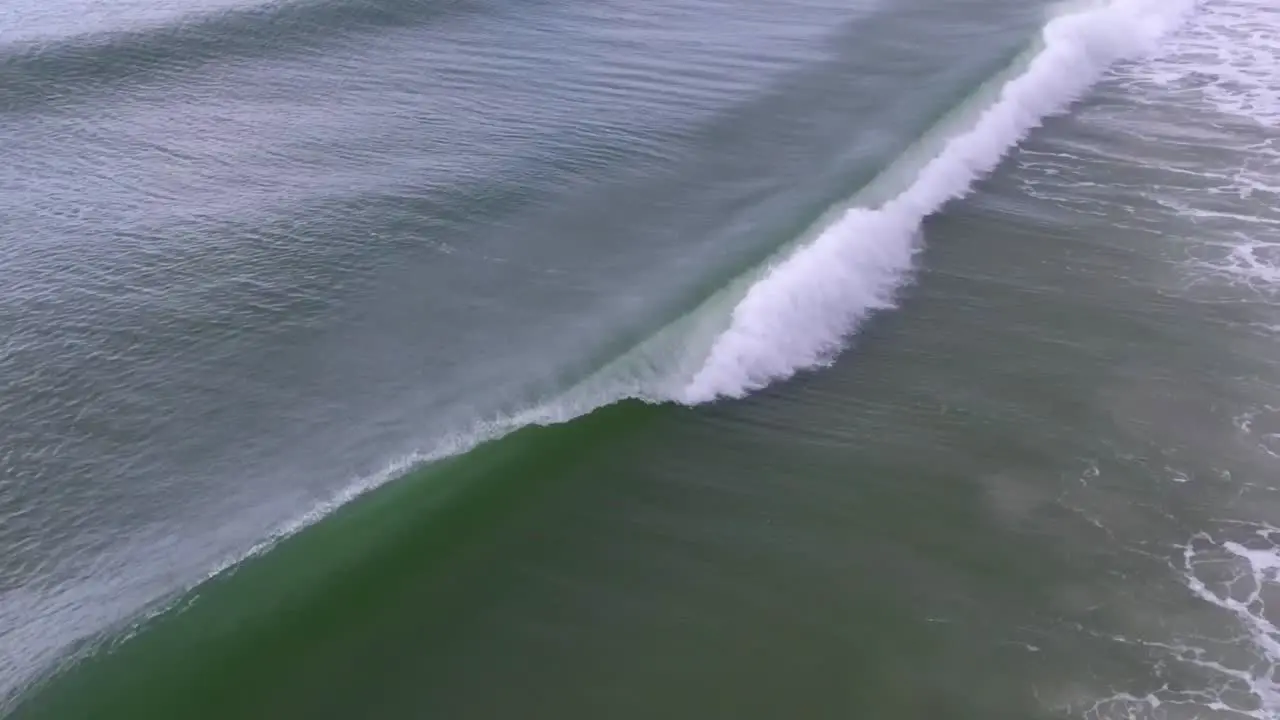 Slow motion drone footage of an ocean wave breaking offshore