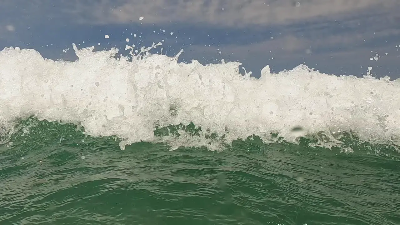 Water surface point of view of old bearded active man with arms wide open waiting big sea waves splashing on him