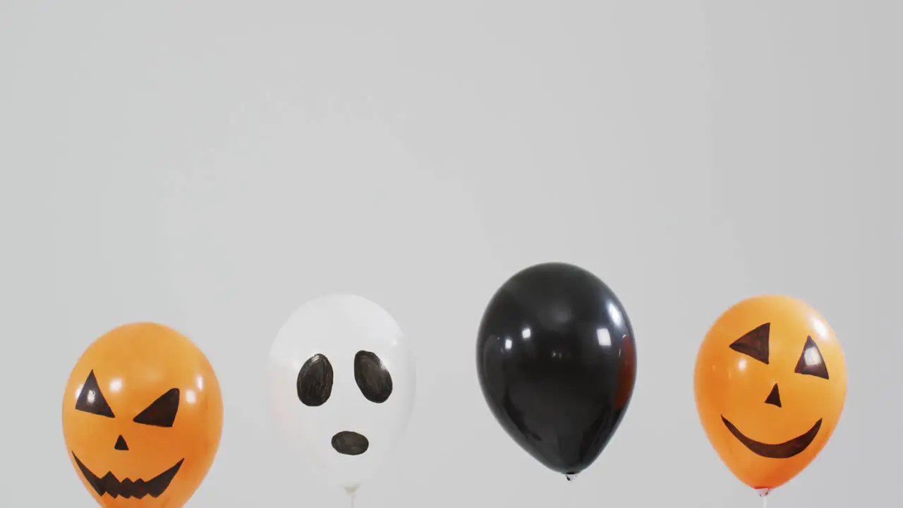 Multiple scary faces printed halloween balloons floating against grey background