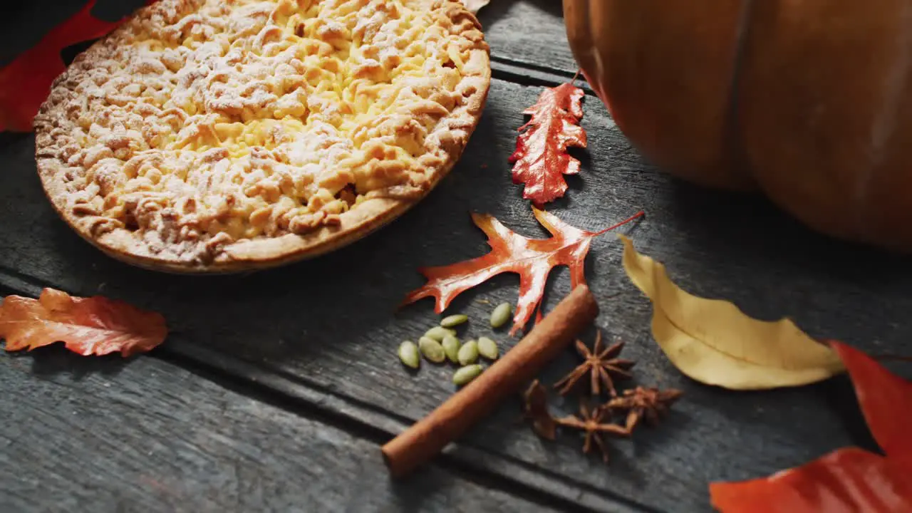 Video of autumn leaves pumpkin spices and pie on wooden background