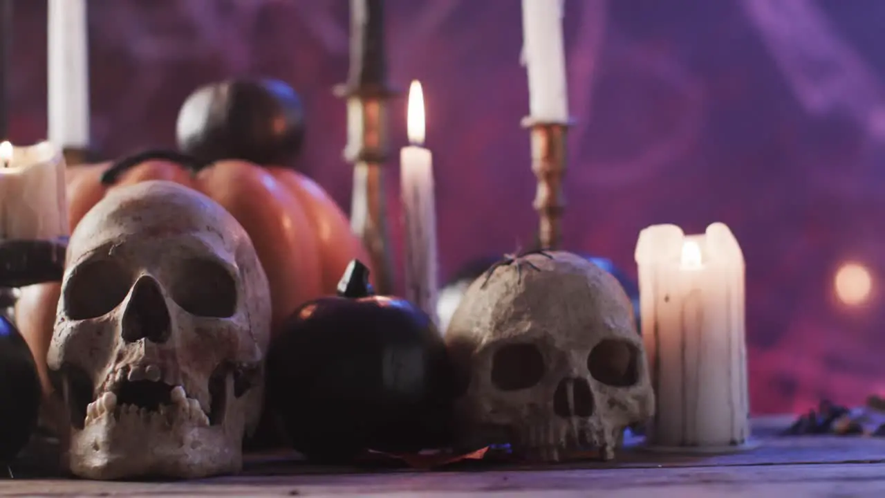 Video of halloween skulls candles and smoke with copy space on purple background