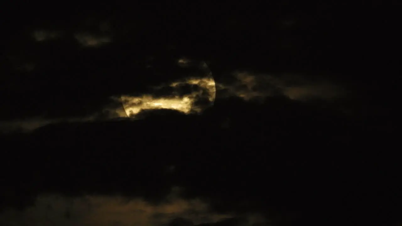 Mystic light coming through behind dramatic clouds during full Moon at night static shot