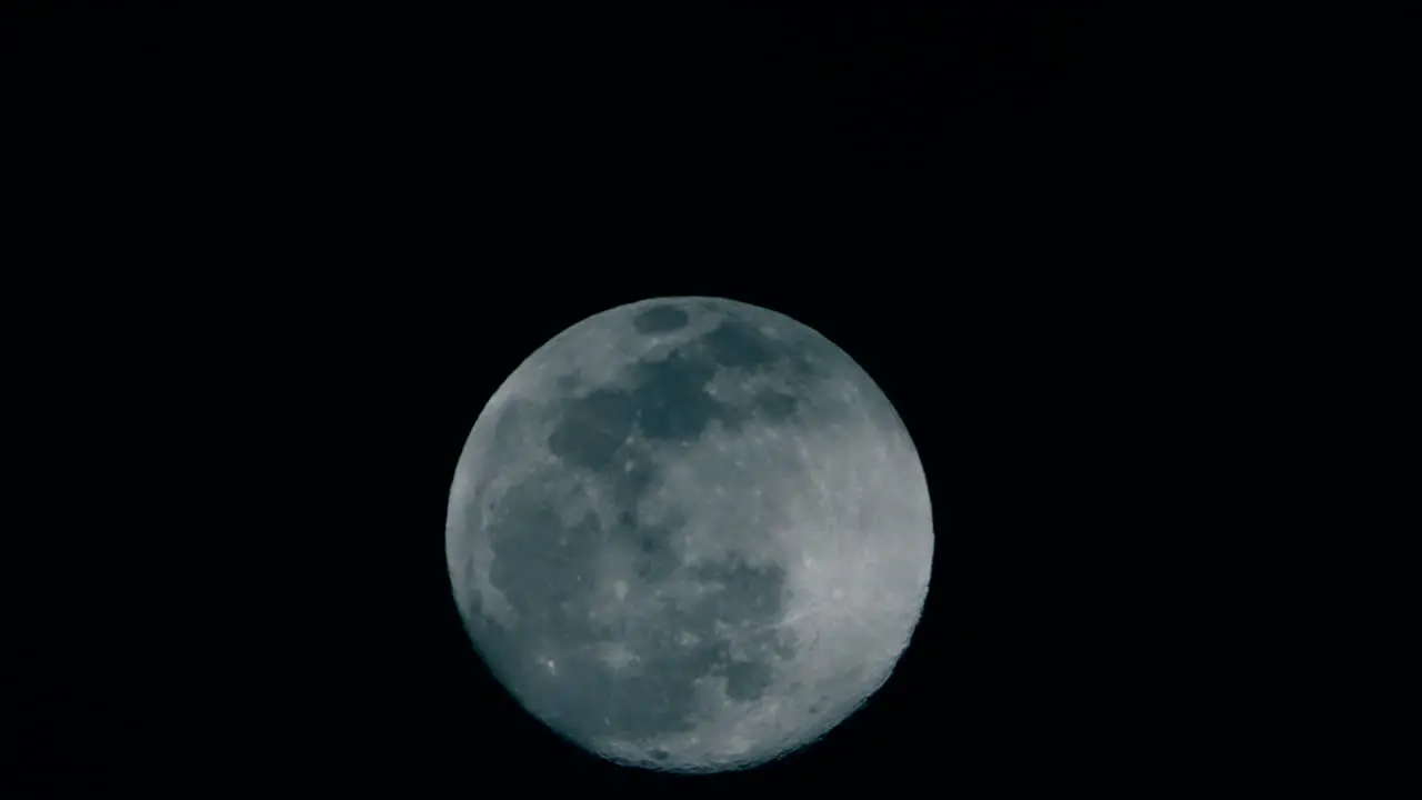 Shot of a full moon slowly rising up in the sky with thin clouds in Tokyo Japan