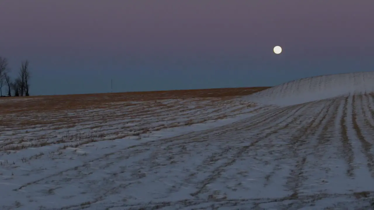 A super moon overtop of a snow covered field