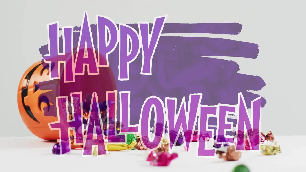 Animation of happy halloween text over pumpkin bucket with sweets