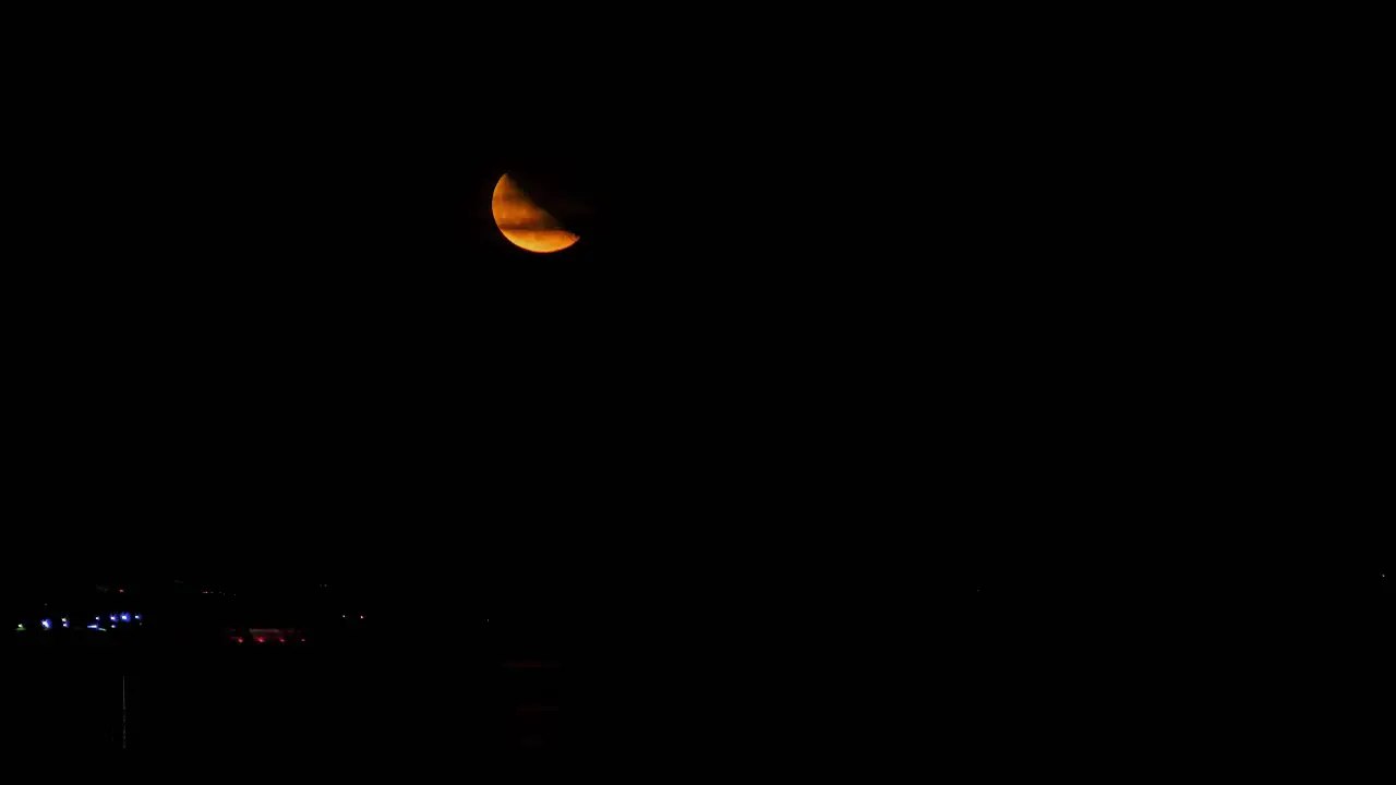 Red half-moon rises over the lake timelapse