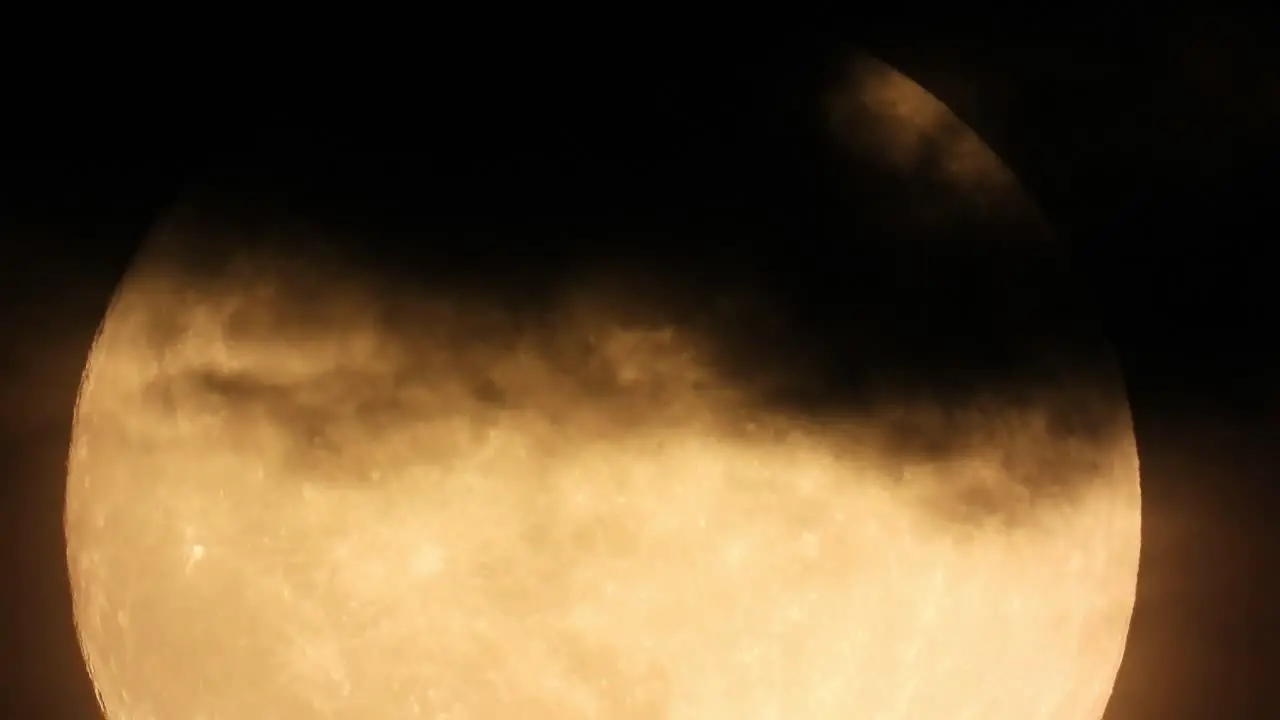 Extreme close-up of Full Moon Moving up Hiding in Black Clouds