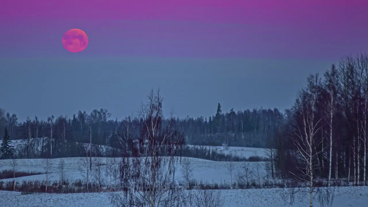 The supermoon sets over a winter landscape then disappears in the clouds time lapse