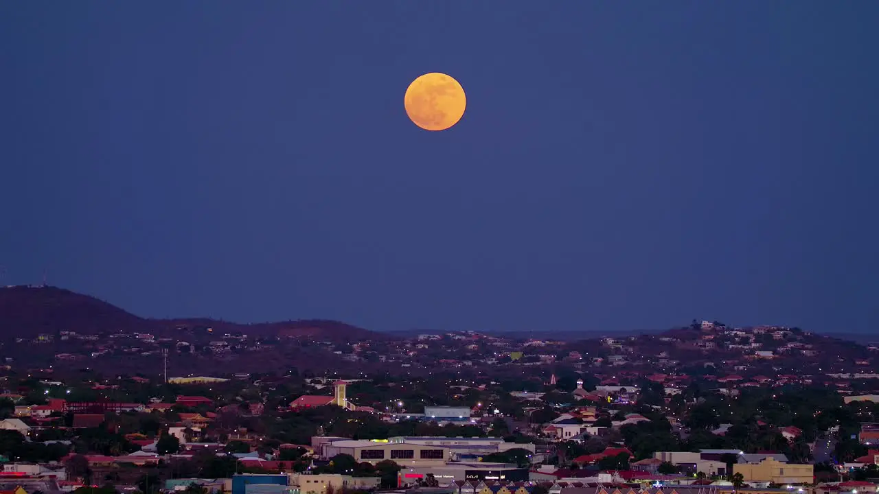 Supermoon sits magnificent in sky red orange tint above willemstad curacao