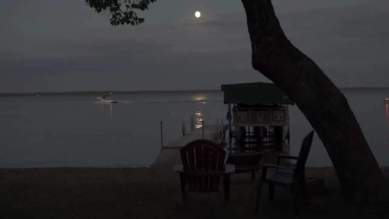 Lake in Bemidji Minnesota during the early evening with a full moon with boats going by in the background