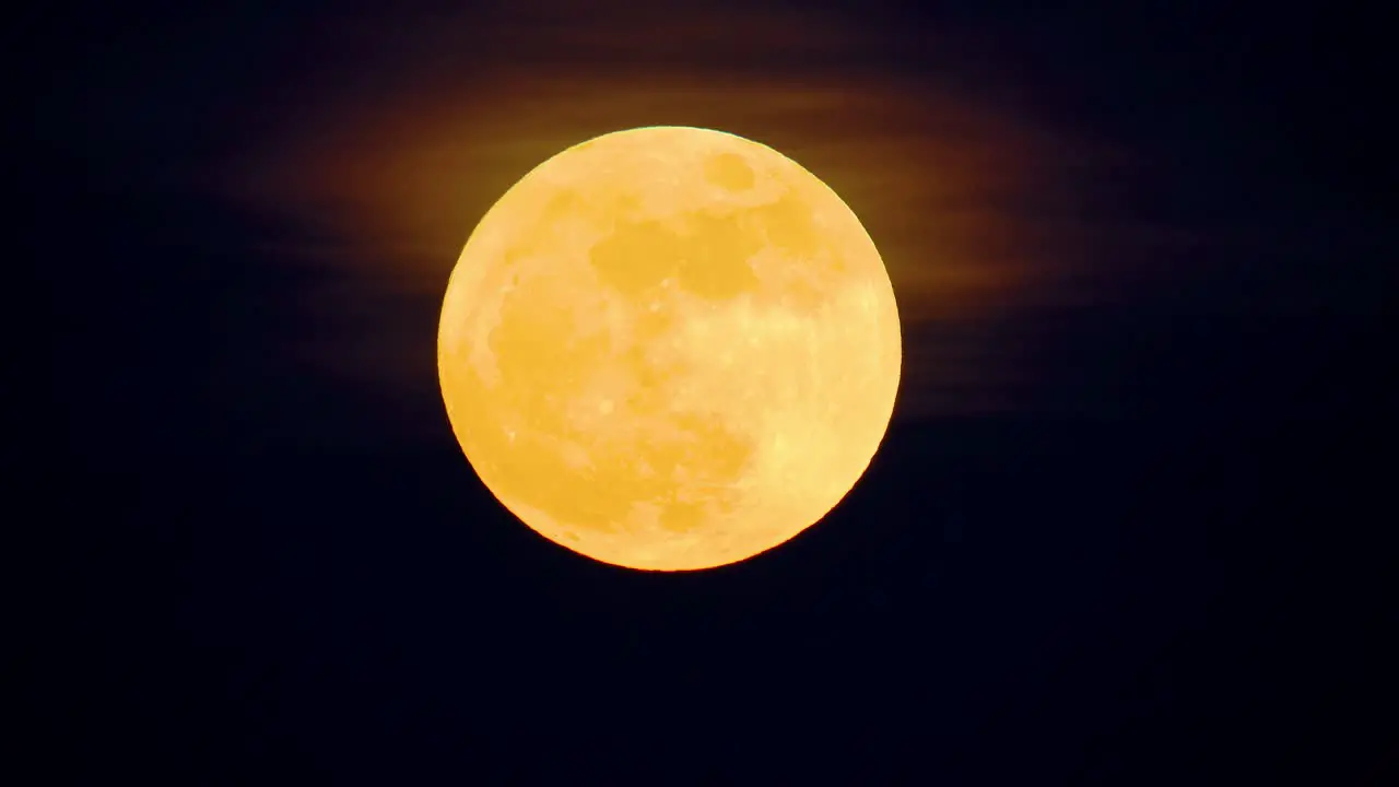 Orange hazey glow above yellow perfect full blue supermoon moon in black sky rising time lapse