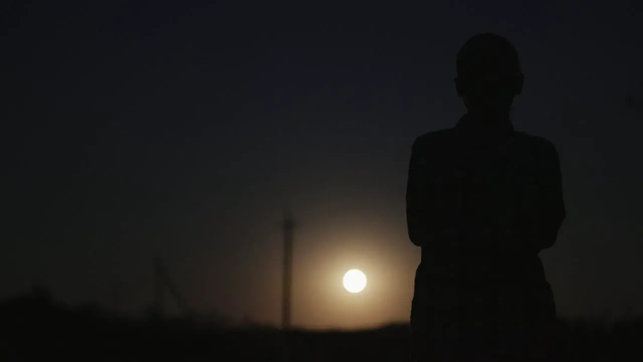 A woman looks at the moon in the dark