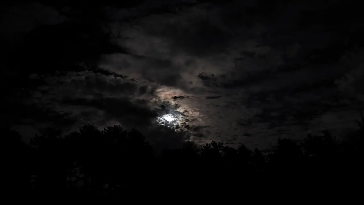 Supermoon shining at night on dark sky over tree forest clouds moving fast over mountains of beautiful romantic background