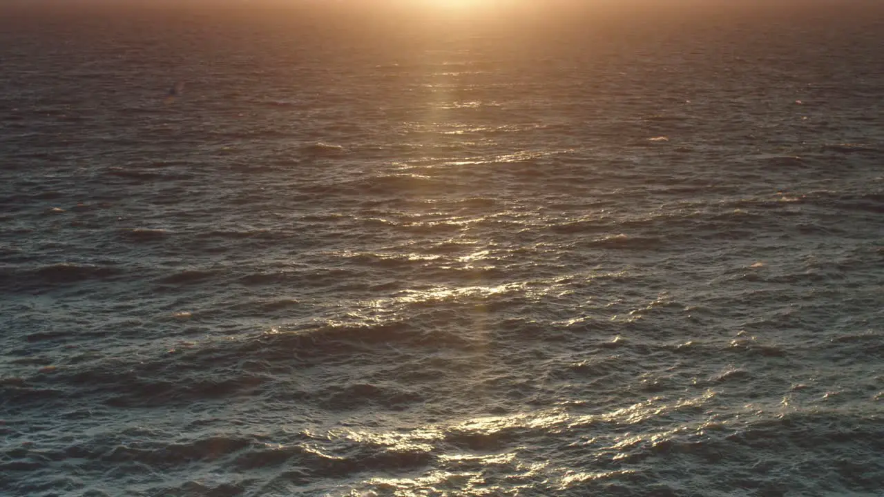 A low sunset reflects onto a choppy sea