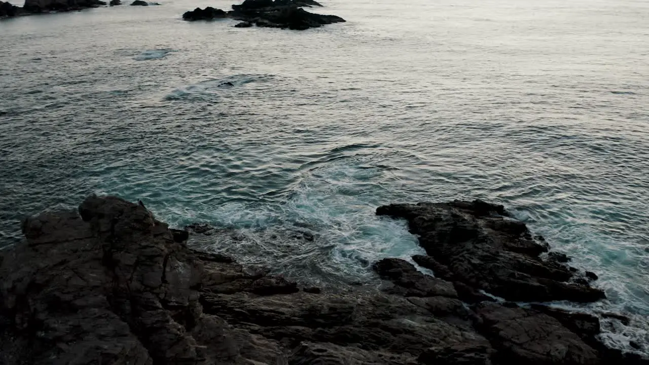 Aerial view rotating shot over a rock formation off the coast of southern Mexico close to Mazunte with waves crashing on at sunset