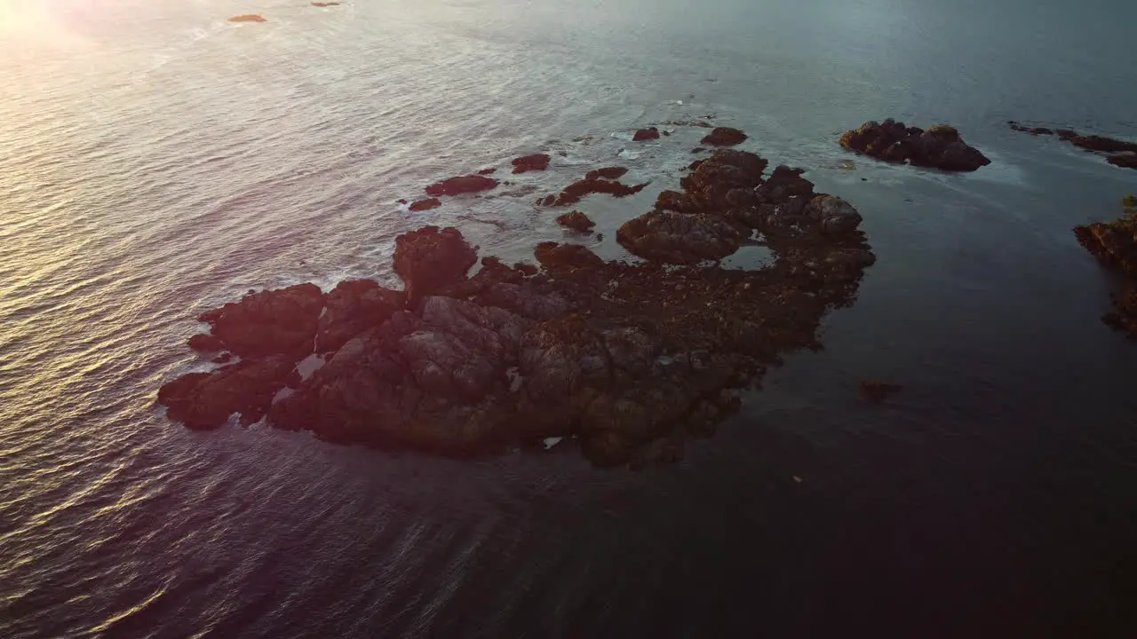 Sunset over a beautiful ocean scene with rocks and waves shimmering in the light