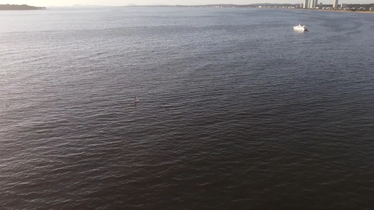 Aerial shot of person paddling on stand up paddle during sunset time on coastline of Atlantic Ocean in Uruguay