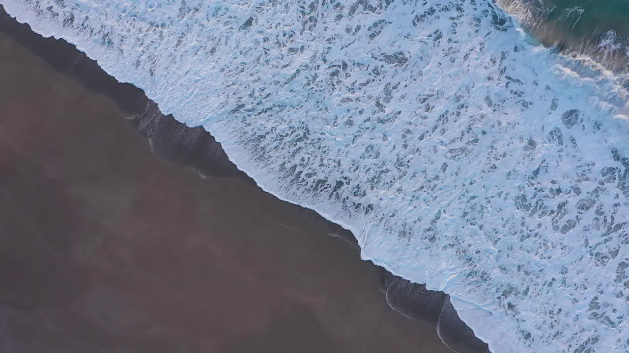 Diagonal drone footage of dynamic ocean waves coming ashore on sand beach