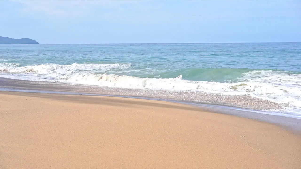 Slow-motion of large swells sliding up on the golden sand of a tropical beach