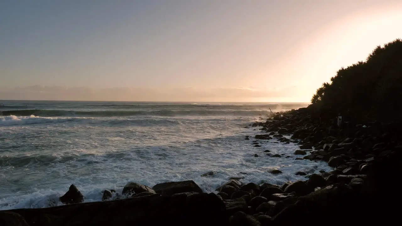 Waves breaking with a man fishing at sunrise at Burleigh Heads on the Gold Coast Queensland Australia