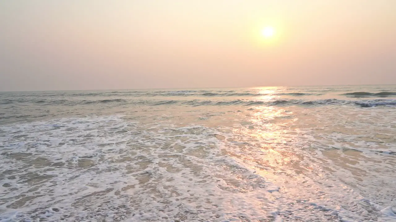 Slow-motion waves washing a short reflect a colorful tropical sunset